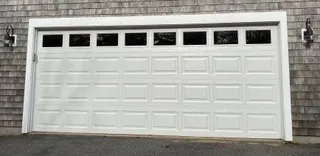 Insulated white double garage door with a window row on a Cape Cod home