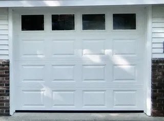 Insulated raised-panel garage door with top windows on a Cape Cod home